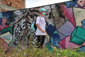 Guía de Bogotá Colors se dirige a invitados a recorridos, al fondo mural de tigre.