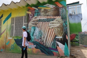 Guía de Bogotá Colors se dirige a invitados a recorridos, al fondo mural de músico tradicional