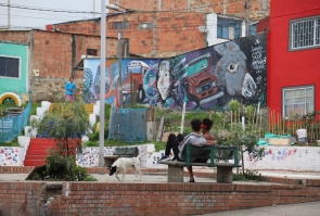 Mural gigante sobre mural de cancha deportiva, dos chicos sentados observan el mural