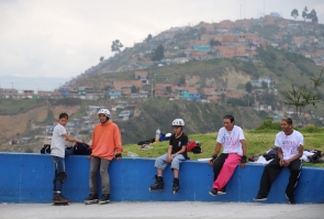 depostistas extremos esperan turno para usar pista de skate, al fondo plano general de barrio sobre montaña