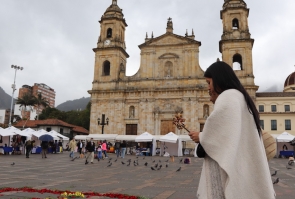 Grupo de indígenas realizan ritual en la Plaza de Bolívar, al fondo catedral y adorno floral en el piso