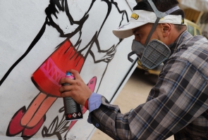 artista realiza grafiti sobre carreta
