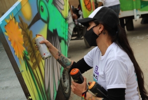 mujer artista realiza grafiti sobre carreta, aerosol en la mano