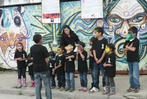 Grupo de niños y niñas con mascaras realizando una presentación