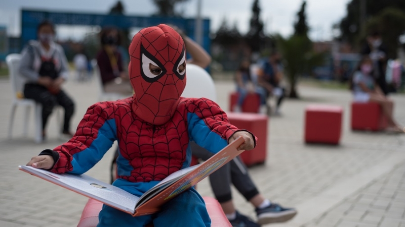 Niño disfrazado del hombre araña leyendo un libro