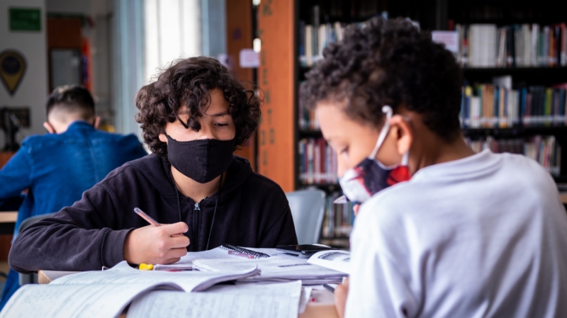 Dos niños en biblioteca haciendo tareas