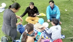 Familia en picnic con libros y cometas acomapañados de referente institucional